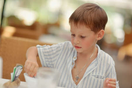cute blond boy with rosy cheeks in a light shirtの写真素材