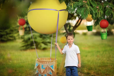 on the green grass boy stands near a hot air balloon with a basket