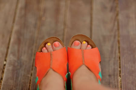 Beautiful female legs pedicure at the girl standing in a beautiful orange shoesの写真素材