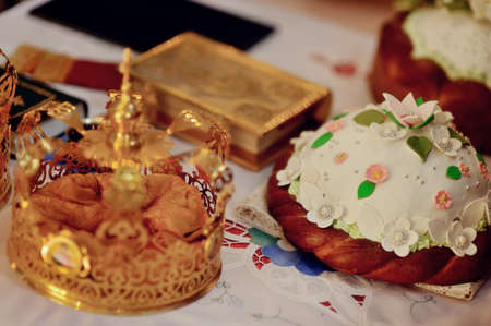accessories for wedding in a church on a table decorated with flowers loaf, bible and crown