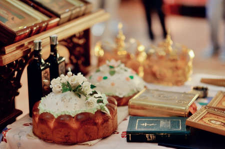 accessories for wedding in a church on a table decorated with flowers and a loaf of Bibleの写真素材