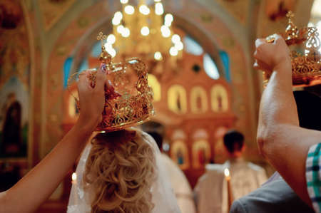 accessories for the wedding in the church in the hands of the crown held over the bride and groomの写真素材