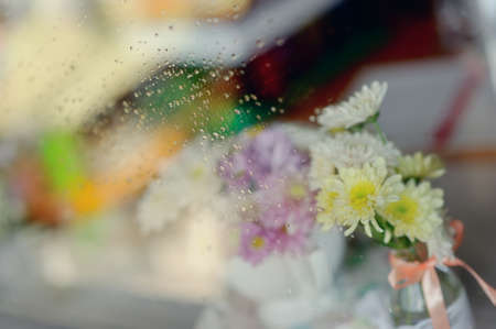 on the windowsill in a wet glass is white vase with a bouquet of flowersの写真素材