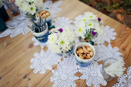 on a beautiful white table cloth and delicate bouquets of flowers and cups with cookiesの写真素材