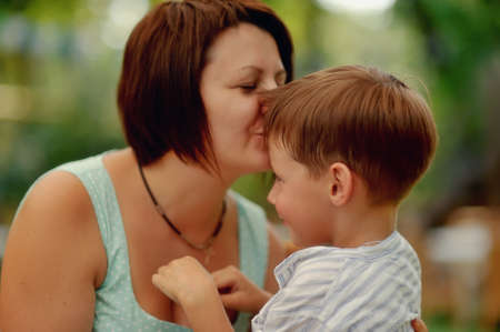 Portrait of an affectionate and loving mother kissing her baby sonの写真素材