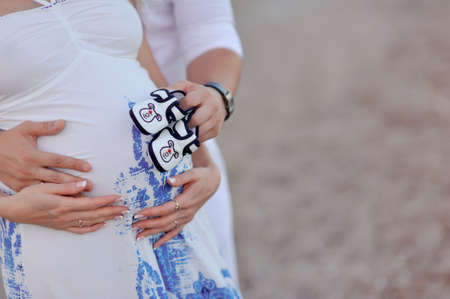on the abdomen of pregnant women caring hands of his father and mother