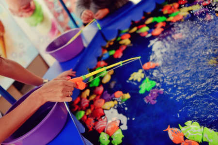 amusement park fun fishing pool with water and bright colored fishの写真素材