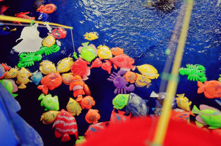 amusement park fun fishing pool with water and bright colored fishの写真素材