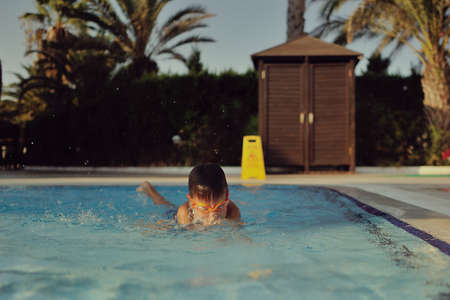 hot sunny day boy with glasses in the swimming poolの写真素材