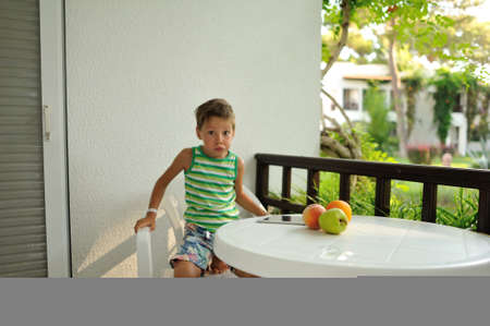 a cute boy at a white table with fruitの写真素材