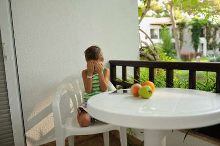 a cute boy at a white table with fruitの写真素材