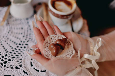 woman s hands holding a white napkin on two chocolates in a heartの写真素材