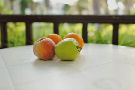fruit still life on a table with a white cloth lying fruit peach, apple and orangeの写真素材