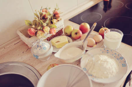 on the kitchen table decorative vase with flowers apples, a glass of milk and butterの写真素材