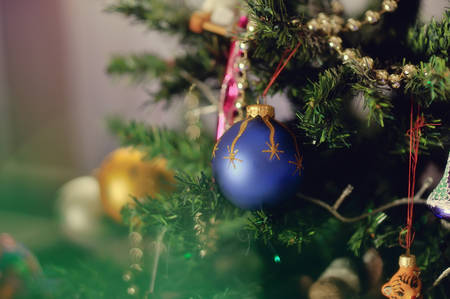 against the backdrop of a Christmas tree decorated with toys hanging beautiful blue ballの写真素材