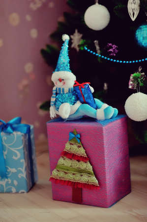 On the background of the Christmas tree, decorated with a large box of toys and gifts and snowmanの写真素材