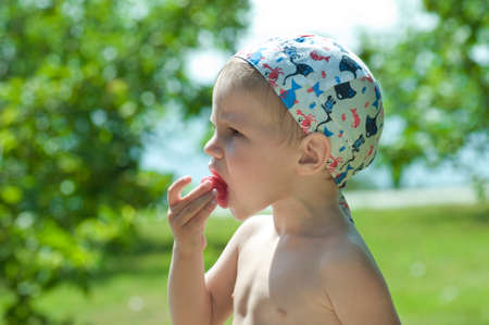 Portrait of a cute kid eats red strawberryの写真素材