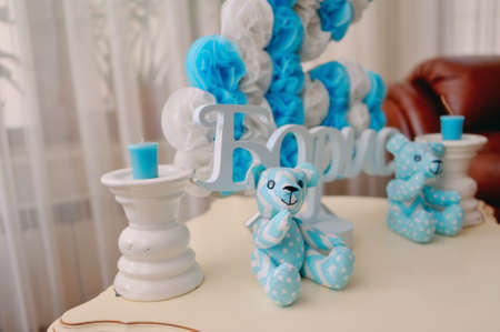 festive decoration in blue and white colors of paper flowers, candles and toy bearの写真素材