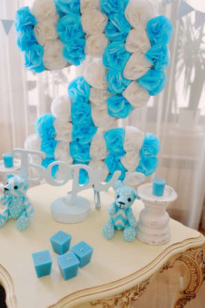 festive decoration in blue and white colors of paper flowers, candles and toy bearの写真素材