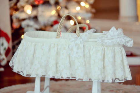 snowy Christmas tree decorated with red balls and white delicate baby bedの写真素材