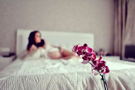 of a white girl with a big bed bud burgundy orchidの写真素材
