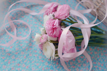 on a blue background is a delicate bouquet of buttercups with ribbonの写真素材