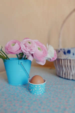 beautiful and delicate bouquet of buttercups in a blue bucket and egg in a basketの写真素材