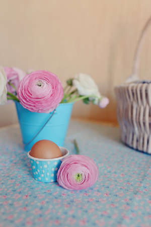 beautiful and delicate bouquet of buttercups in a blue bucket and egg in a basketの写真素材