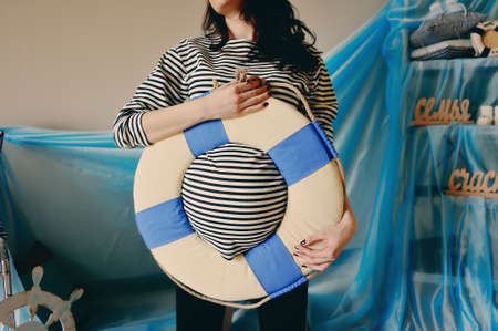 pregnant woman holding a life preserver vest on his stomachの写真素材