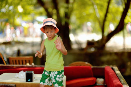 Outdoors on a red couch resting fun boy in a hatの写真素材