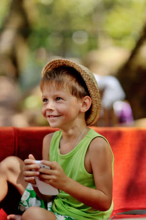 Outdoors on a red couch resting fun boy in a hat with phoneの写真素材