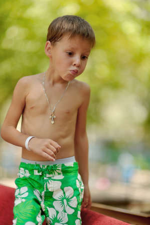 cute boy dressed only in green shorts with surprise on his faceの写真素材