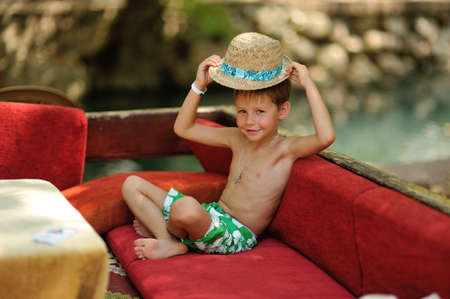 Outdoors on a red couch resting fun boy in a hatの写真素材