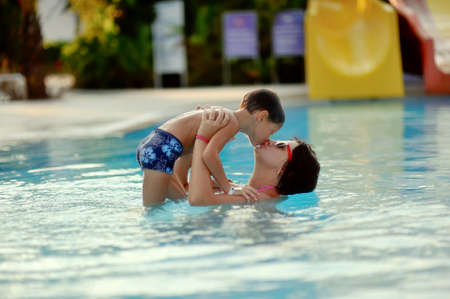Mom and son having fun in the summer playing in the poolの写真素材