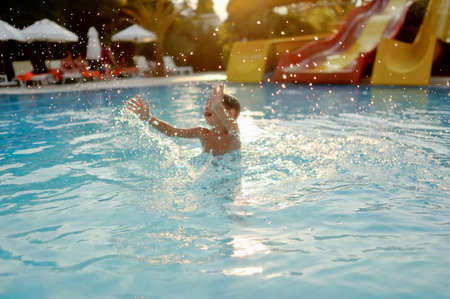 hot summer day, the boy fun dives and swims in the poolの写真素材