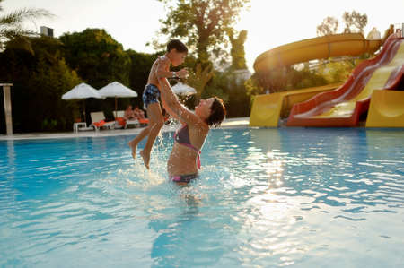 Mom and son having fun in the summer playing in the pool