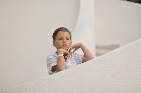 cute little boy in white shirt standing on white stairsの写真素材