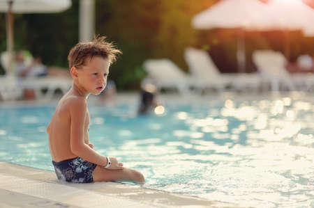 hot summer day, the boy fun dives and swims in the poolの写真素材