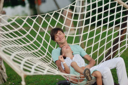 a summer day on the nature of the father and son rest in the big white hammockの写真素材
