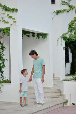 father and son standing near a house with a white wall of a summer dayの写真素材