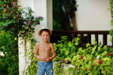 little boy in shorts and straw hat in a flower garden at homeの写真素材