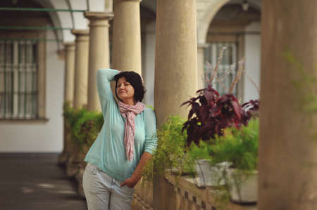 woman in trousers posing in antique balcony with stone pillars and railingsの写真素材