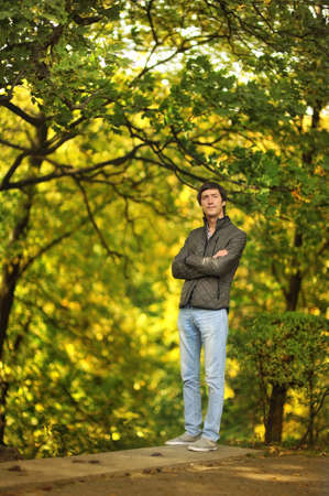 against the backdrop of autumn trees man in jacket and jeans for a walk in the park