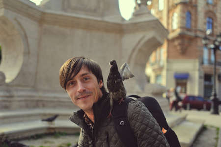 in the town square of a young man with a backpack and doveの写真素材