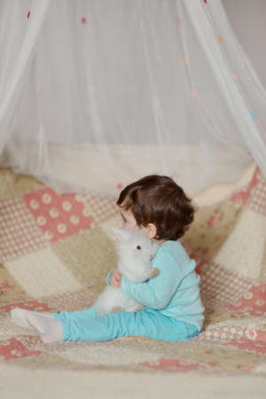 little girl in a blue suit hugging a fluffy white rabbit