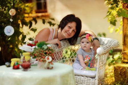 summer holiday garden at the table with berries and jam spins sitting woman with cute kidの写真素材