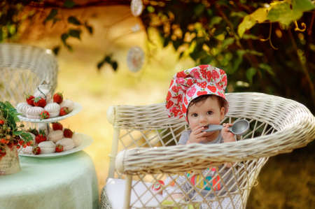 Outdoors in the garden on a wicker chair cute girl in toqueの写真素材