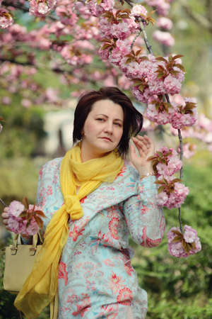 cherry blossoms in the garden and a woman in a colorful dress and yellow scarfの写真素材
