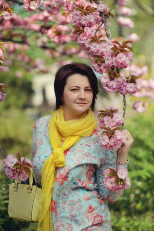 cherry blossoms in the garden and a woman in a colorful dress and yellow scarfの写真素材