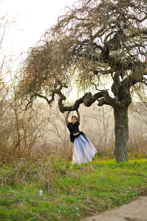 in the sunlight forest girl white skirt and black jacket standing near treeの写真素材